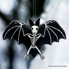 a black and white skeleton bat ornament hanging from a chain