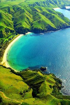 an aerial view of the ocean and land surrounding it, with mountains in the background