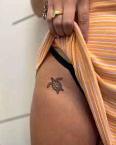 a woman's thigh with a small tattoo of a turtle on the back of her leg