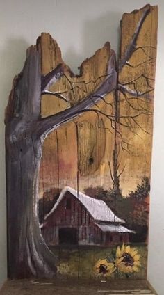 a piece of wood with a barn and sunflowers painted on it, in front of a white wall