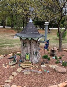 a tree stump with a house built into it in the middle of a park area