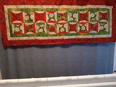 a red and green quilt hanging on the wall