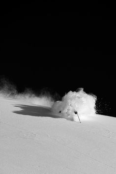 a man riding skis down the side of a snow covered slope under a dark sky