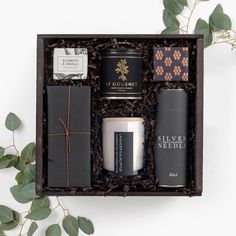 an open gift box containing three different types of coffee and teas, with greenery in the background