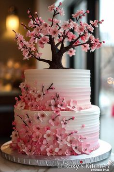 a three tiered cake with pink flowers on the side and a tree topper