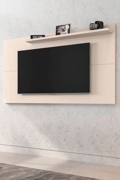 an entertainment center with a flat screen tv mounted on it's side, in front of a white wall