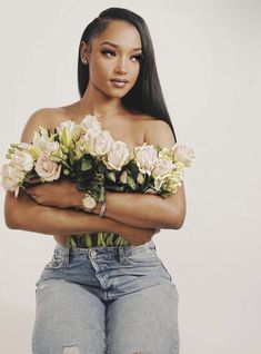 a woman wearing ripped jeans and holding flowers