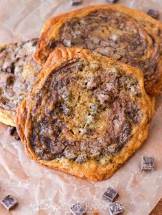 three chocolate chip cookies sitting on top of a piece of wax paper