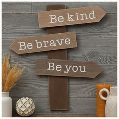 a wooden sign that says be kind, be brave, be you with arrows pointing in different directions