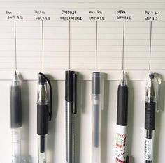 several pens are lined up on a wall with the names of different pens attached to it