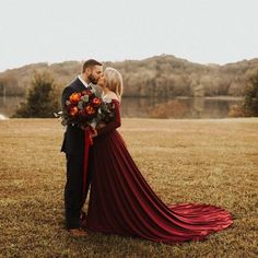 a bride and groom standing in a field with their arms around each other as they kiss