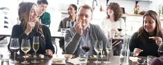 a group of people sitting around a table with wine glasses on it and food in front of them