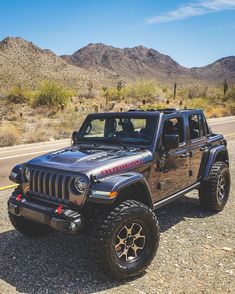 the jeep is parked on the side of the road in front of mountains and cactus