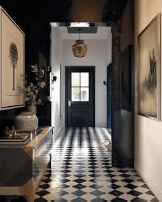 a hallway with black and white checkered flooring, framed pictures on the wall