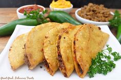 some tacos are on a white plate with green peppers