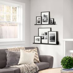 a living room with gray couches and pictures on the wall above them in black and white