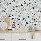 a kitchen with white cabinets and black and white wallpaper on the walls behind it