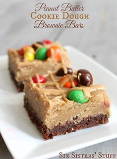 two pieces of peanut butter cookie dough brownie bars on a white plate with candy candies