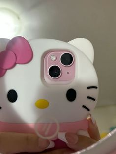 a person holding a cell phone with a hello kitty case on it