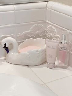 a swan shaped soap dish sits on the bathroom counter next to a bottle of lotion