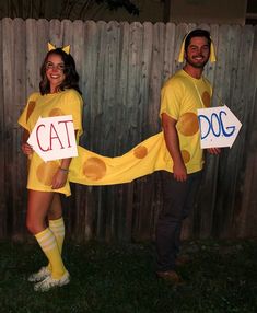 two people dressed in costumes standing next to each other holding signs that say cat and dog