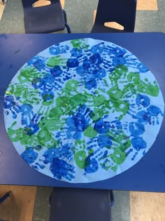 a paper plate with blue and green handprints sitting on top of a table