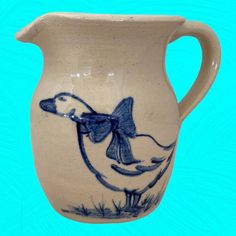 a blue and white pitcher with a duck on it's side, in front of a blue background