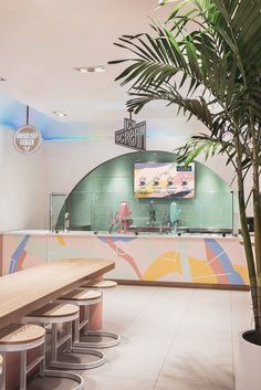 the interior of a restaurant with tables and stools next to a large palm tree