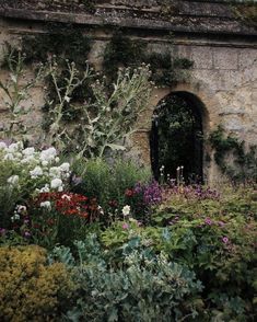 an old stone building surrounded by flowers and plants