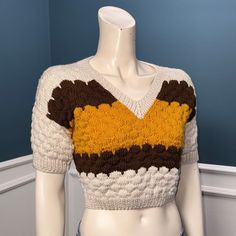 a white mannequin wearing a brown and yellow sweater