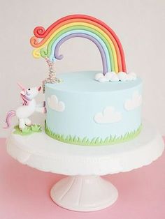 there is a cake with a rainbow decoration on the top and a unicorn figurine next to it