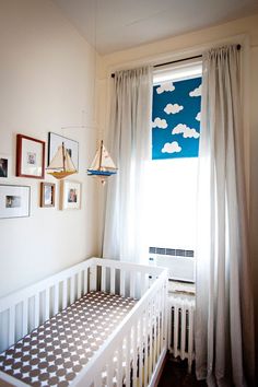 a white crib in front of a window with pictures on the wall