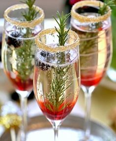 two glasses filled with liquid and garnished with herbs