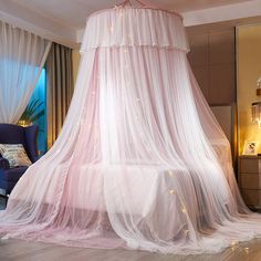 a pink canopy bed in a bedroom next to a blue chair