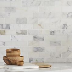 a white marble tile backsplash with wooden bowls