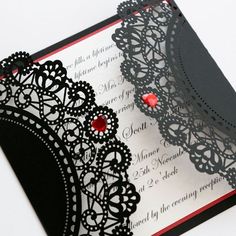 a black and white wedding card with red jeweles on it's side,