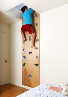 a young boy climbing up the side of a wall with his feet on a bed