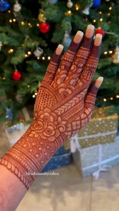 a woman's hand with henna on it in front of a christmas tree