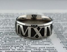 a ring with roman numerals on it sitting on top of an open book