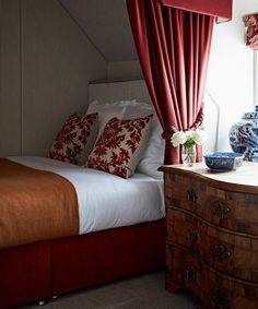 a bedroom with a bed, dresser and vases on top of the table in front of it