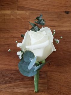 a single white rose on a wooden surface