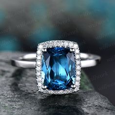 an engagement ring with a blue topazte surrounded by white diamonds on a rock