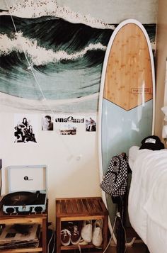 a bedroom with a surfboard on the wall next to two small tables and a record player