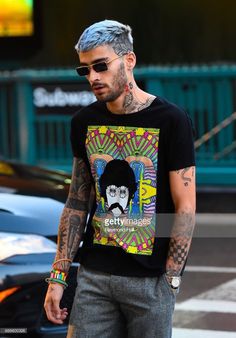 a tattooed man with grey hair and sunglasses on the street