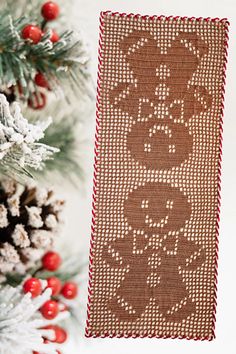 a knitted christmas stocking hanging from a tree with pine cones in the background