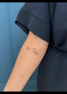 a woman's arm with a small mountain tattoo on the left side of her arm