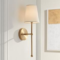 a wall light with a white shade on it's side next to a door