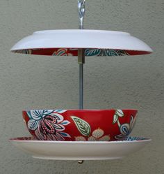 a red and white bowl hanging from a metal hook with two plates on it's sides