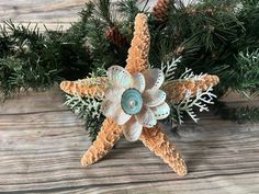 a starfish ornament is sitting on a wooden table next to pine branches