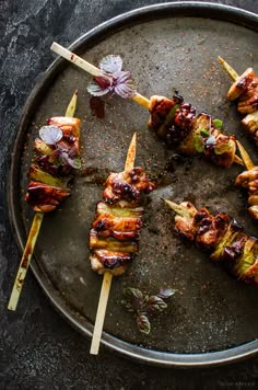 several skewered meats are on a plate with toothpicks and garnishes